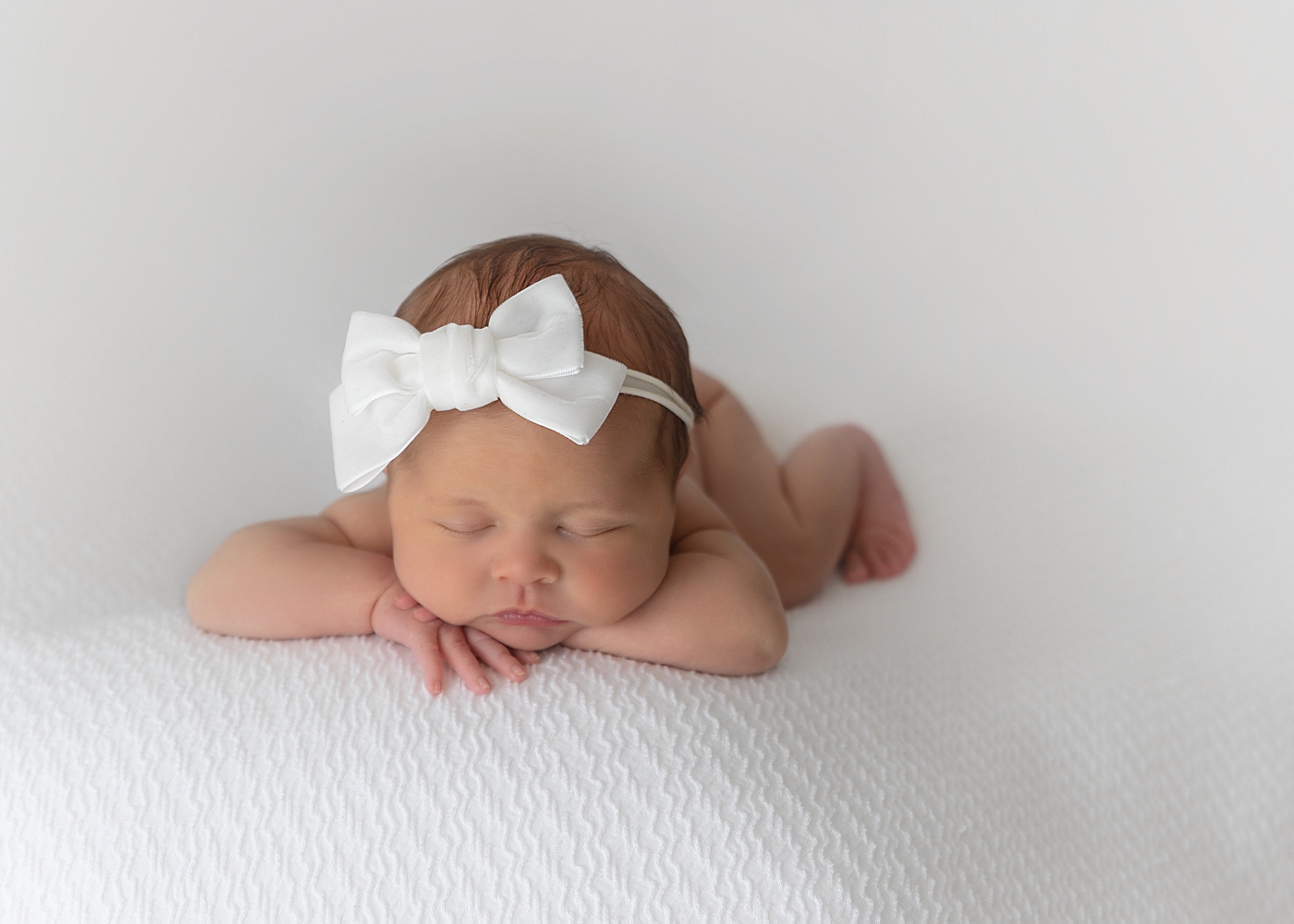 Newborn baby girl on her belly for photos with Rachel Brookes Photography.