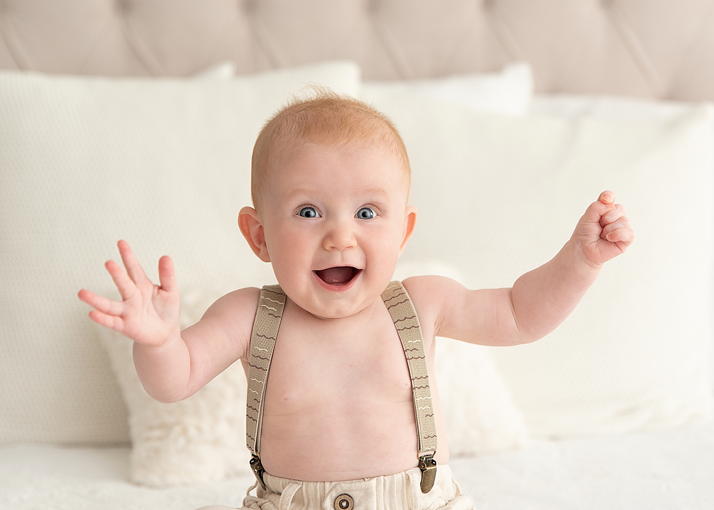 Six month old little boy wearing suspenders and has the biggest smile on his face. Photo by Rachel Brookes Photography.