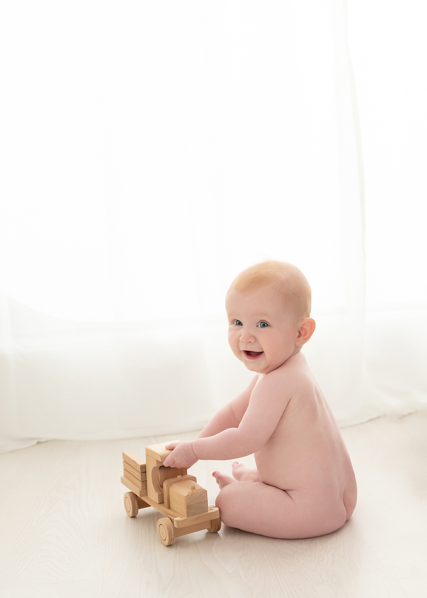 Baby boy playing with wood truck at milestone session with Rachel Brookes Photography, a Chagrin Falls baby photographer.