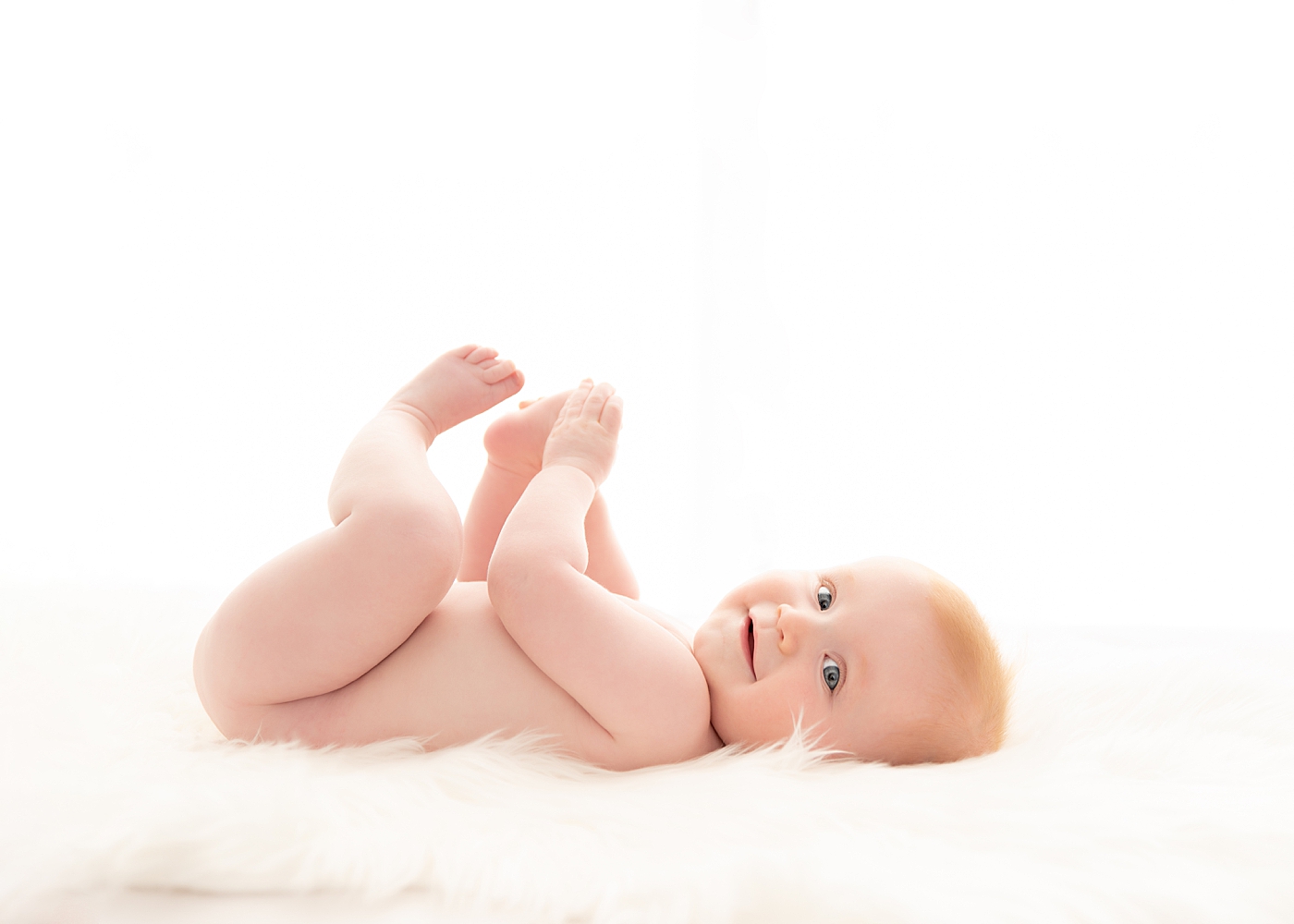 Baby boy laying on his back playing with his feet. Photo by Chagrin Falls baby photographer, Rachel Brookes Photography.