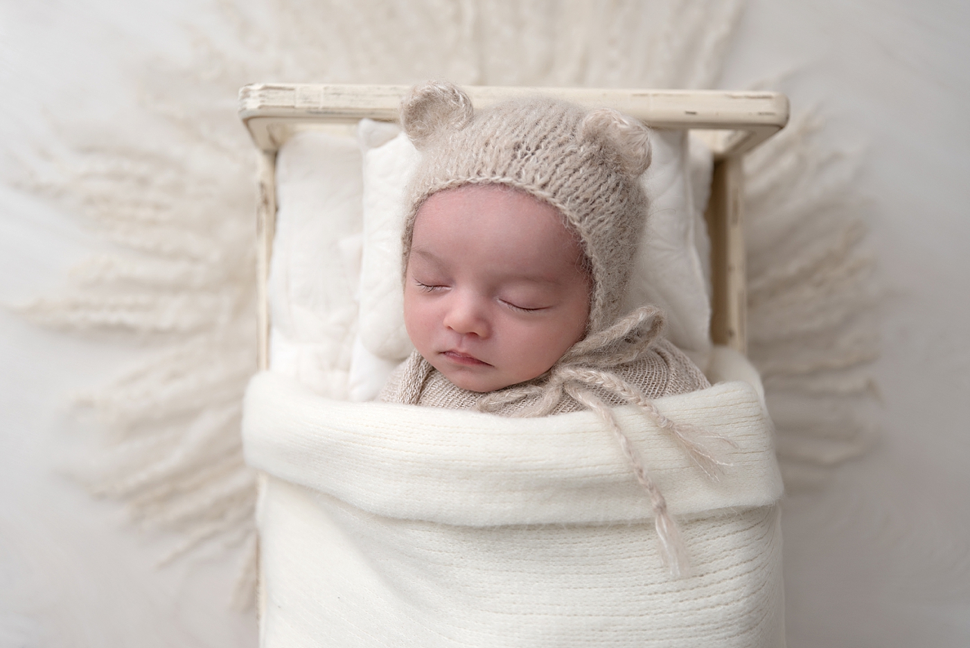 Newborn sleeping on small baby bed for newborn photos. Photo by Rachel Brookes Photography.