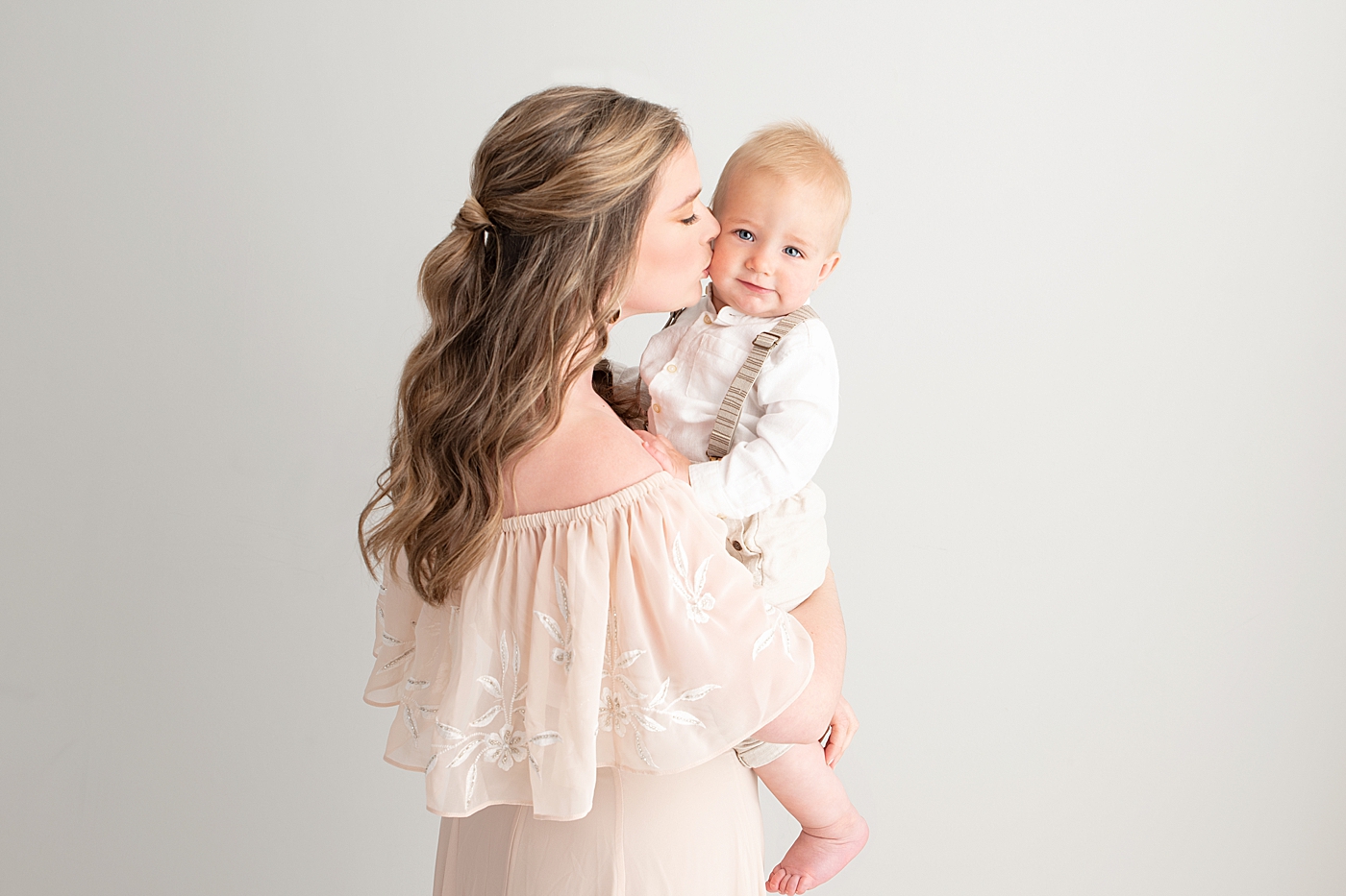 Mom giving her son a kiss on the cheek during his first birthday cake smash session with Cleveland Photographer, Rachel Brookes Photography.