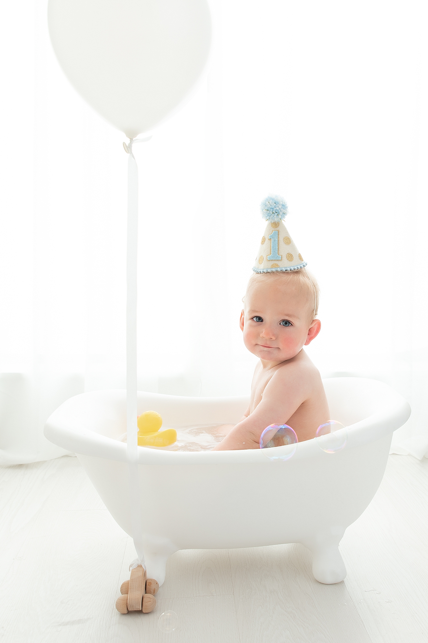 Bubble bath at the end of a cake smash session for one year old. Photo by Rachel Brookes Photography.