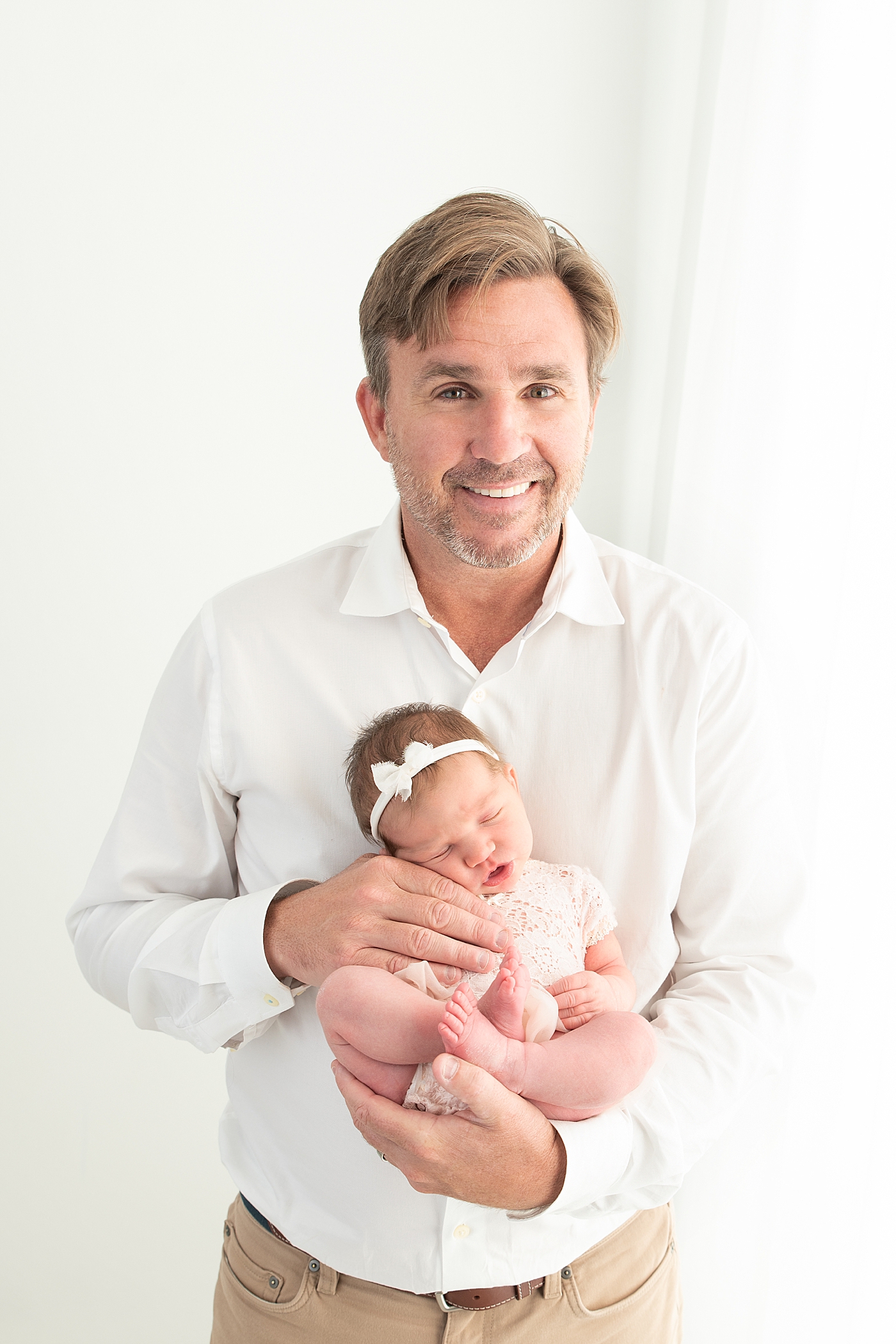 Dad holding his daughter for newborn photos. Photo by Rachel Brookes Photography.